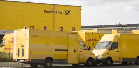 Mehrere Transporter der Deutschen Post vor einem Logistikzentrum.