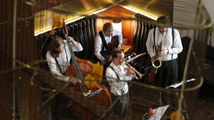 Eine Jazzband im Foyer des Stadttheaters mit Trompete, Saxofon, Kontrabass und Schlagzeug.