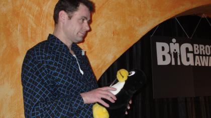 padeluun auf der Bühne im Bunker Ulmenwall mit einem Pinguin-Stofftier in der Hand.