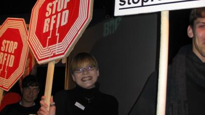 Mehrere Personen mit "STOP RFID"-Schildern in der Hand.