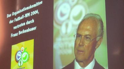 Franz Beckenbauer ist per Beamer-Bild an eine Landweind projeziert.