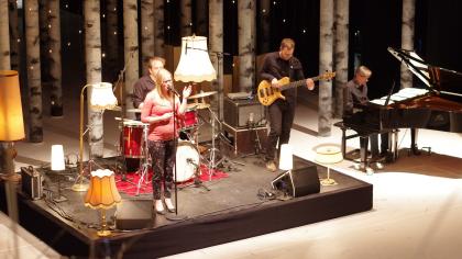 Eine Band performt einen Song auf der BBA-Bühne, im Hintergrund viele Birkenstämme.