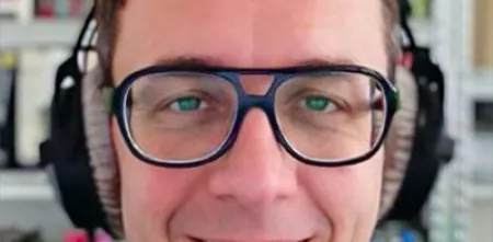 Lächelndes Gesicht von Hans Hübner mit Brille und Kopfhörern auf