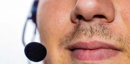 Detailaufnahme eines Gesichts (Nase-Mund-Partie) von einer Person mit einem Headset.