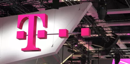 Logo der Deutschen Telekom als Leuchtreklame in einer Messehalle.