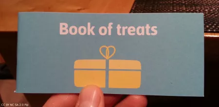 Kärtchen mit der Aufschrift: "Book of treats". Darunter eine Grafil eines Geschenks in gelb auf grünlichem Grund.