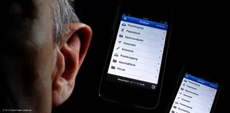 Silhouette eines Kopfes (ein Ohr im Fokus). Rechts daneben zwei helle Smartphone-Bildschirme auf dunklem Hintergrund.