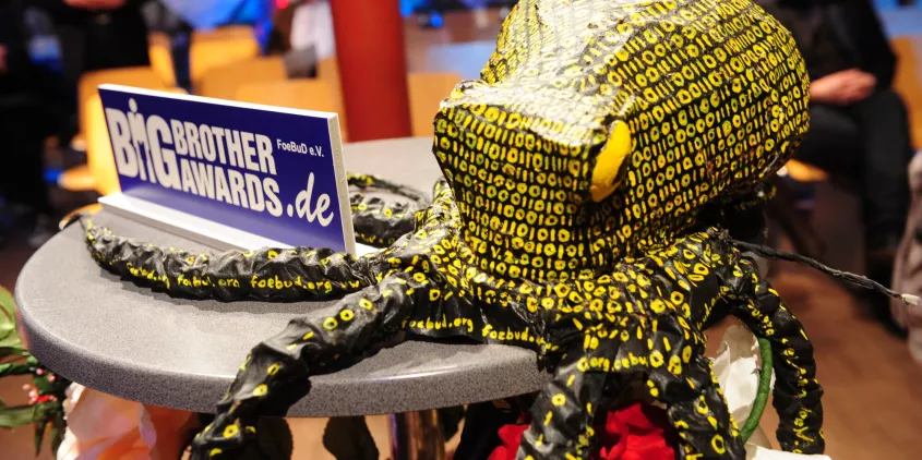 Die Datenkrake neben einem Schild der BigBrotherAwards auf einem Stehtisch während der BBA-Gala.