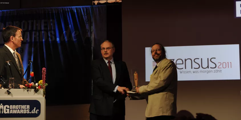 Werner Hülsmann übergibt auf der Bühne den BigBrotherAward an Herrn Prof. Dr. Gert G. Wagner.