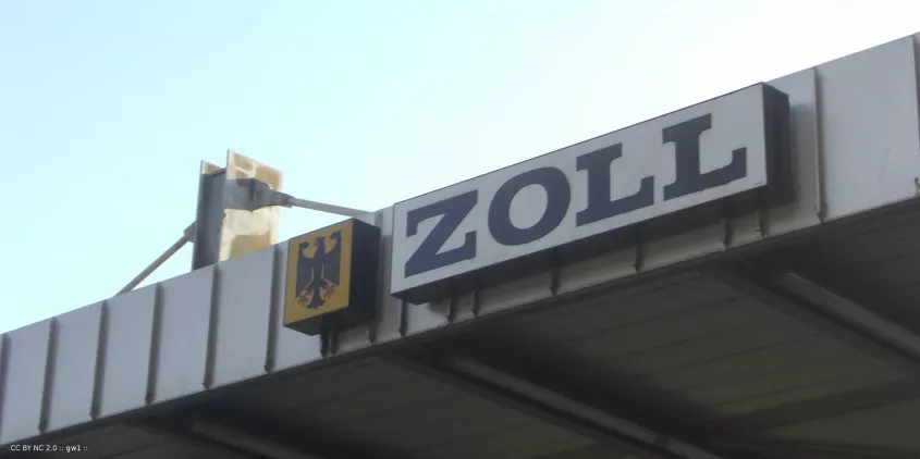 Detailaufnahme einer Zollstation mit dem Hinweisschild „Zoll“.