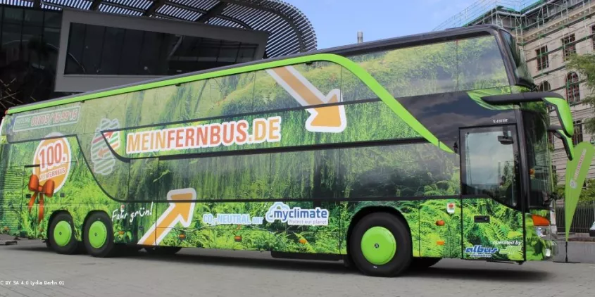 Seitenansicht eines MeinFernbus-Busses (Werbung mit viel grün und orangenem Logo).