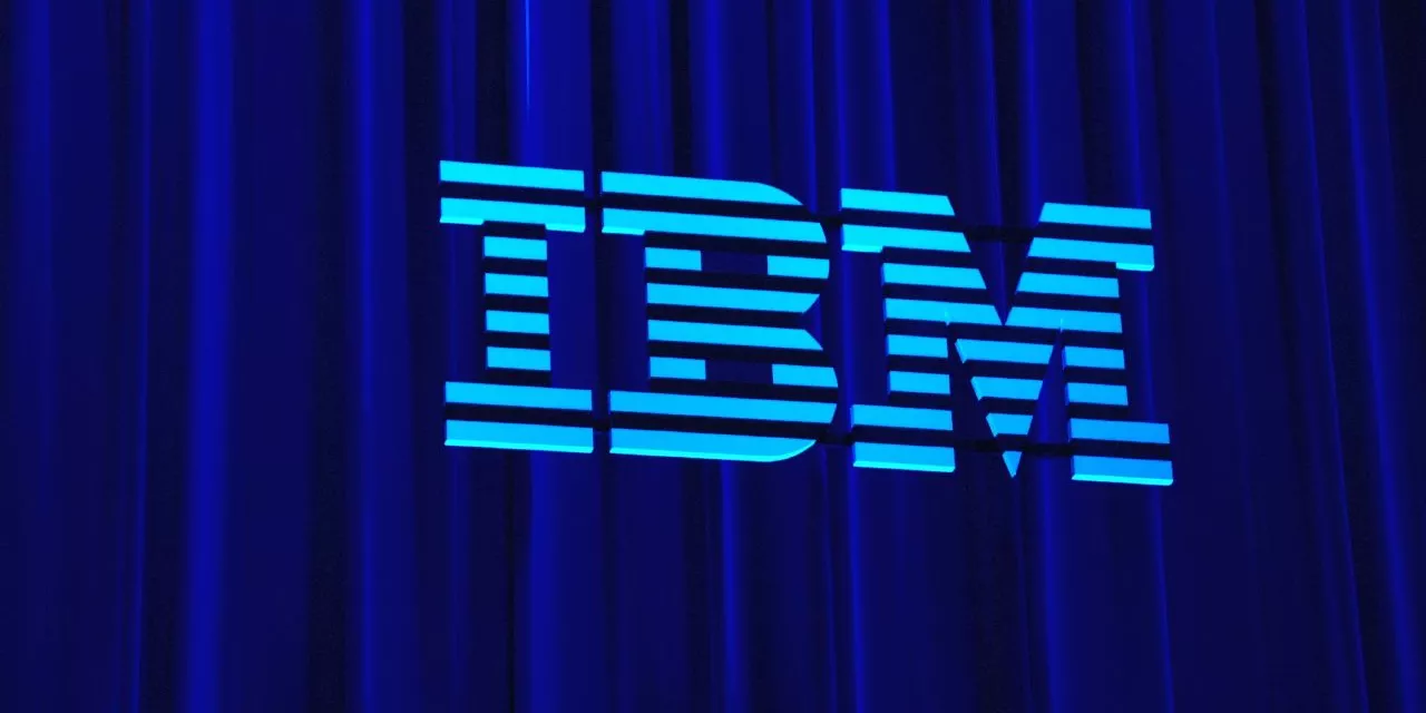 Logo von IBM (hellblau) an einen Vorhang (dunkelblau) gestrahlt.