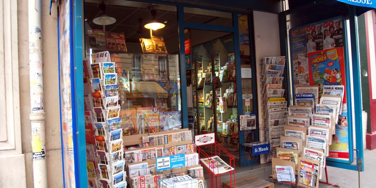Blick auf ein Geschäft mit vielen Zeitungen neben dem Eingang.