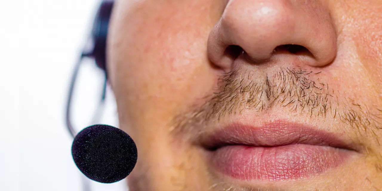 Detailaufnahme eines Gesichts (Nase-Mund-Partie) von einer Person mit einem Headset.
