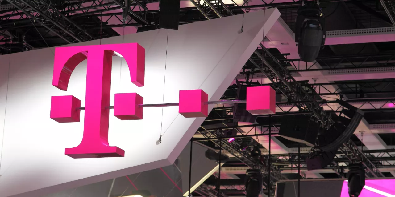 Logo der Deutschen Telekom als Leuchtreklame in einer Messehalle.