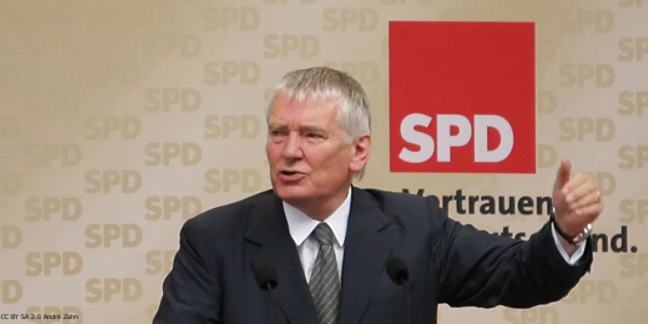 Otto Schily bei einer Wahlkampfkundgebung der SPD in München. Er hebt eine Hand hoch während er am Rednerpult steht.