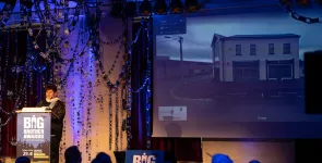 Rena Tangens während ihrer Laudatio am Redner.innenpult. Im Hintergrund das Gebäude der Irischen DPC.