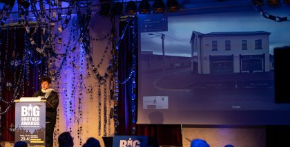 Rena Tangens während ihrer Laudatio am Redner.innenpult. Im Hintergrund das Gebäude der Irischen DPC.