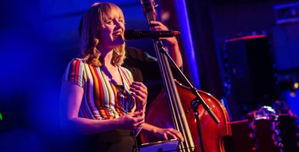 Kristin Shey am Mikrofon während einer musikalischen Darbiertung.