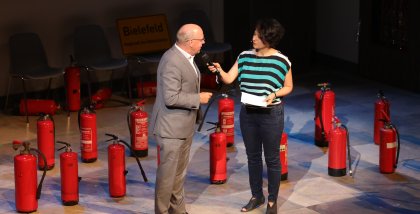 Peter Wedde wird von Golineh Atai interviewt. Im Hintergrund Feuerlöscher.