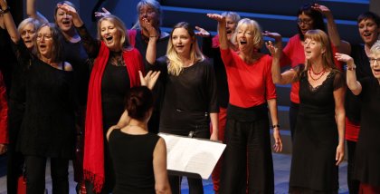 Der Chor "One Voice" sing auf der Bühne (Kleidung in schwarz/rot).