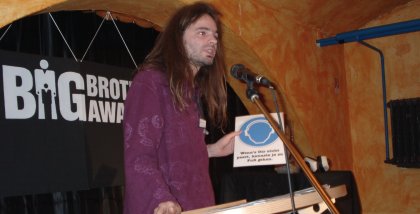 Sebastian Lisken am Redner.innenpult mit einem Schild in der Hand.