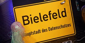 Bühnendeko: Ortseingangsschild von Bielefeld. Darunter der Text: „Hauptstadt des Datenschutzes“.