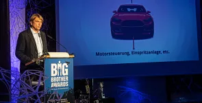 Frank Rosengart am Redner.innenpult. Im Hintergrund ein Auto.