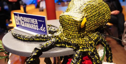 Die Datenkrake neben einem Schild der BigBrotherAwards auf einem Stehtisch während der BBA-Gala.