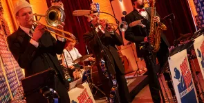 Vier Musiker.innen mit Posaune, Trompete, Saxophon und Schlagzeug.