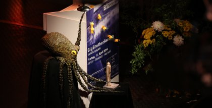 Das Redner.innenpult geschmückt mit der Datenkrake, der BBA-Statue und einem Blumenstrauß.