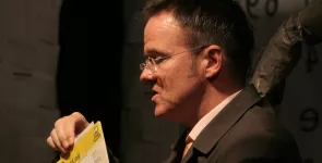 Andreas Liebold am Redner.innenpult mit einer Karte in der Hand.