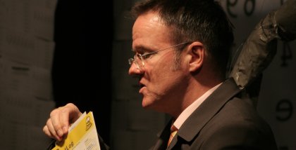 Andreas Liebold am Redner.innenpult mit einer Karte in der Hand.