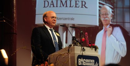Prof. Dr. Peter Wedde am Redner.innenpult. Im Hintergrund das Daimler-Logo.