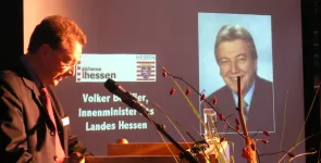 Fredrik Roggan am Redner.innenpult. Im Hintergrund ein Foto von Volker Bouffier.