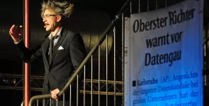 Eine Person mit zauseligen Haaren auf einer Treppe. Rechts daneben ein Banner mit der Aufschrift „Oberster Richter warnt vor Datengau“.
