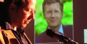 Werner Hülsmann am Redner.innenpult. Im Hintergrund ein Foto von Christian Wulff.