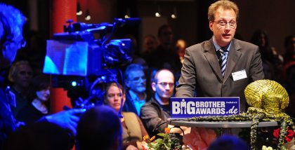 Fredrik Roggan am Redner.innenpult. Im Hintergrund das Publikum.