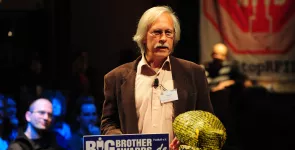 Rolf Gössner am Redner.innenpult. Darauf die Datenkrake.