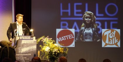 Linus Neumann am Redner.innenpult. Im Hintergrund eine Barbie und Logos von Mattel und Toy Talk.