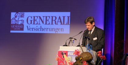 padeluun am Redner.innenpult. Im Hintergrund das Logo der Generali Versicherungen.