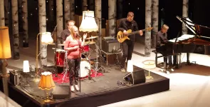 Eine Band performt einen Song auf der BBA-Bühne, im Hintergrund viele Birkenstämme.