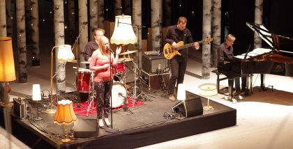 Eine Band performt einen Song auf der BBA-Bühne, im Hintergrund viele Birkenstämme.