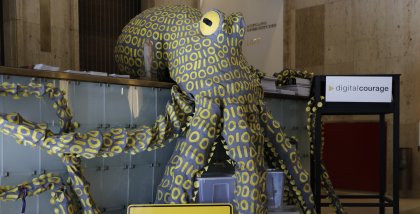 Die Datenkrake im Foyer des Stadttheaters. Die Tentakel sind weit ausgebreitet. Vor ihr ein Schild mit der Aufschrift: „Bielefeld. Hauptstadt des Datenschutzes“.