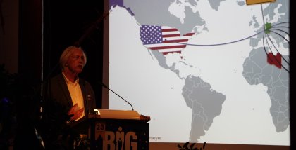 Rolf Gössner am Redner.innenpult. Im Hintergrund eine Landkarte.