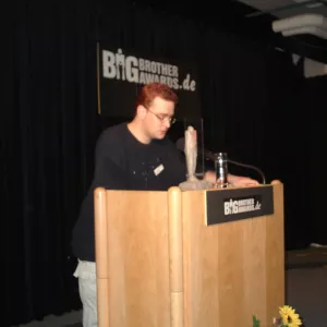 Jens Ohlig am Redner.innenpult zu den BigBrotherAwrds 2001.